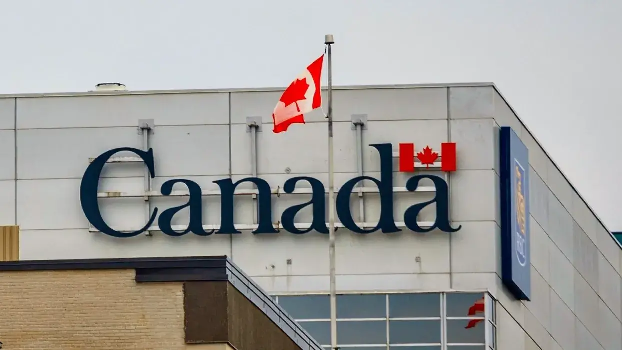 The exterior of a government of canada building with the canadian flag on the rooftop